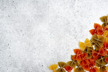 Types of uncooked pasta. Green, yellow and red pasta farfalle dry on a light concrete background. Shooting from above. Flat lay, top view, copy space