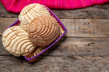 Mexican sweet bread: vanilla and chocolate conchas on wooden background