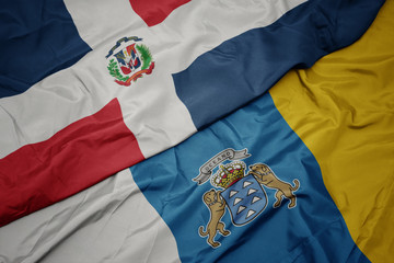 waving colorful flag of canary islands and national flag of dominican republic.