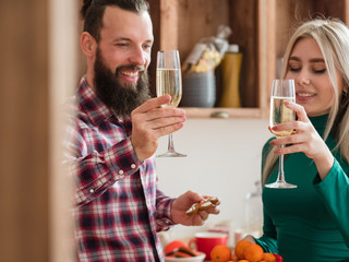 Happy New Year. Cheerful couple drinking champagne in modern kitchen, celebrating winter holidays at home.