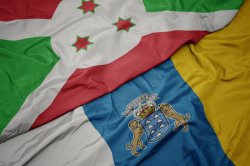 Fototapeta premium waving colorful flag of canary islands and national flag of burundi .