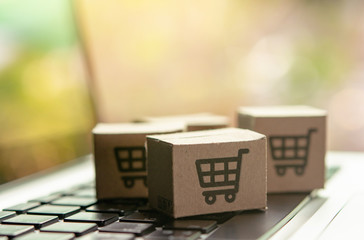 Online shopping - Paper cartons or parcel with a shopping cart logo on a laptop keyboard. Shopping...