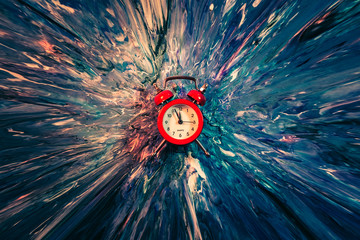 Time flies. Red vintage alarm clock falling down into blue and white paint with splash effect....