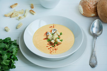 Cheese soup with crackers, herbs and feta cheese. Cream soup served in a white plate. White background.