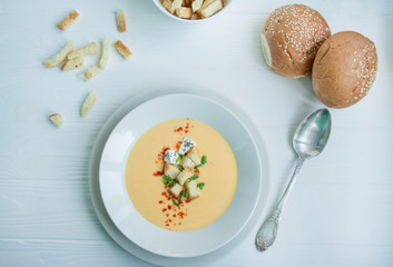 Cheese soup with crackers, herbs and feta cheese. Cream soup served in a white plate. White background.