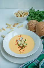 Cheese soup with crackers, herbs and feta cheese. Cream soup served in a white plate. White background.