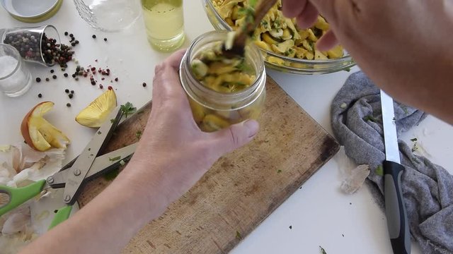 Personal perspective of woman hands preparing Amanita caesarea (known as Caesar's mushroom). Put the mushrooms in jars in oil