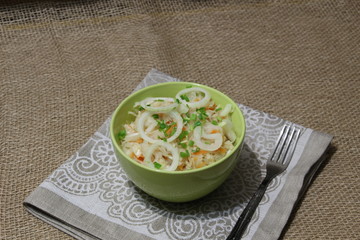 bowl of pickled cabbage with onion on sackcloth background in rustic style