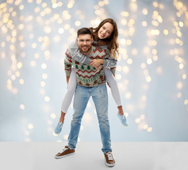 christmas, people and holidays concept - portrait of happy couple having fun at ugly sweater party...