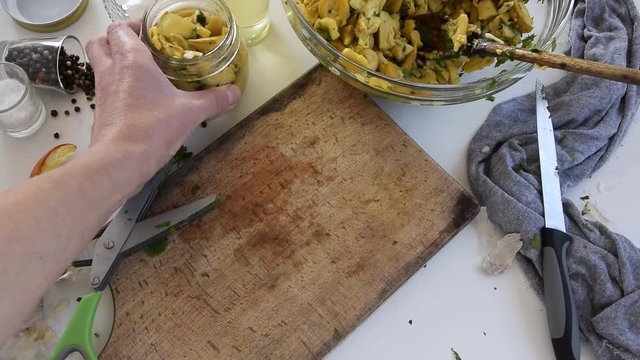 Personal perspective of woman hands preparing Amanita caesarea (known as Caesar's mushroom). Put the mushrooms in jars in oil