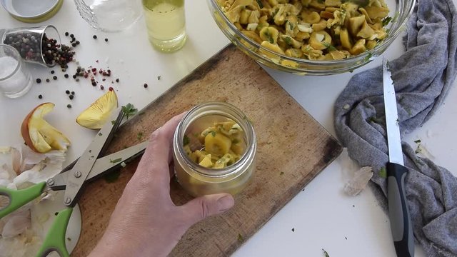 Personal perspective of woman hands preparing Amanita caesarea (known as Caesar's mushroom). Put the mushrooms in jars in oil