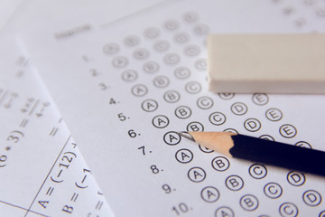 Pencil and eraser on answer sheets or Standardized test form with answers bubbled. multiple choice answer sheet