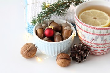 Christmas ball, acorns and cup of tea on white background 