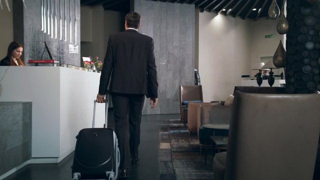 Businessman with travel suitcase arriving in hotel at holiday
