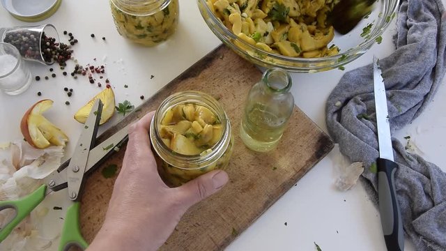 Personal perspective of woman hands preparing Amanita caesarea (known as Caesar's mushroom). Put the mushrooms in jars in oil