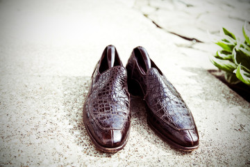 pair of mens black alligator dress shoes on concrete