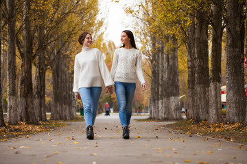 Two girlfriends in a white woolen sweater and blue jeans