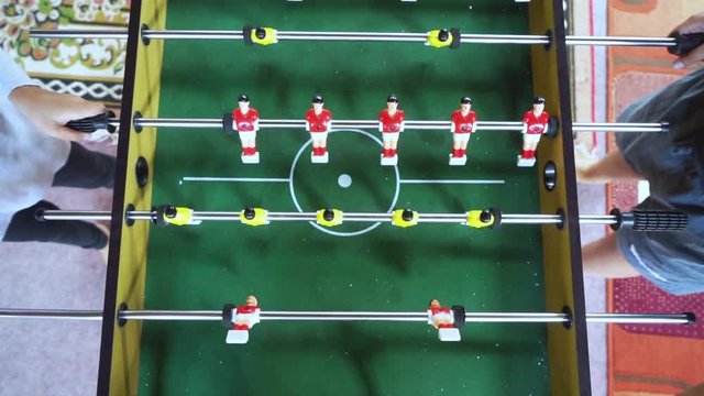 Top view of two people playing foosball table or table soccer during leisure time