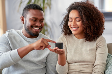 internet of things and technology concept - happy african american couple with smart speaker...