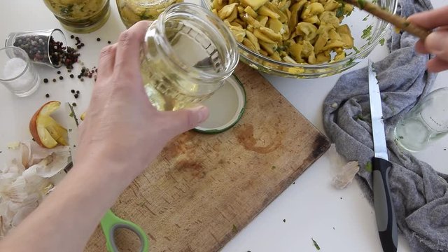 Personal perspective of woman hands preparing Amanita caesarea (known as Caesar's mushroom). Put the mushrooms in jars in oil
