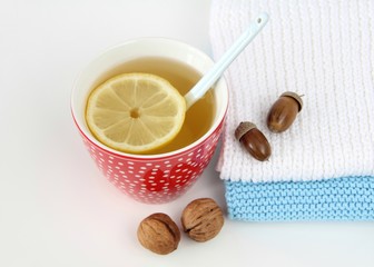 acorns, cup of tea and knitted scarves on a white table