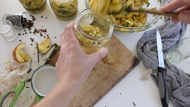 Personal perspective of woman hands preparing Amanita caesarea (known as Caesar's mushroom). Put the mushrooms in jars in oil