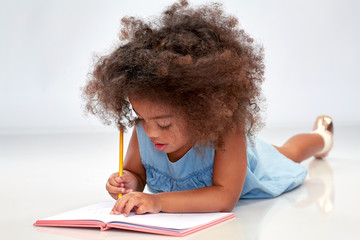 childhood, creativity, drawing and people concept - happy little african american girl with...
