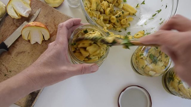 Personal perspective of woman hands preparing Amanita caesarea (known as Caesar's mushroom). Put the mushrooms in jars in oil