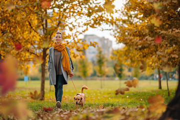 Woman and small brown dog enjoying in the park in autumn