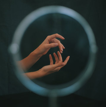 Two gesturing hands reflected in circular mirror