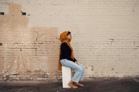 Profile of woman in hijab sitting on stool