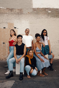 Portrait of group of friends pose outside by brick wall