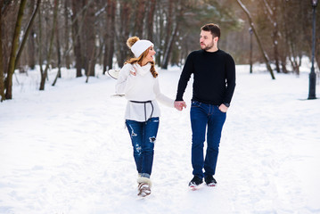 Fototapeta na wymiar Loving couple walking on a date in a winter Park. On the girl's back hanging a pair of skates.