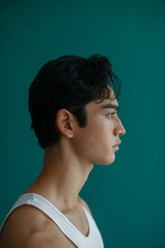 Portrait of a young man with earring on turquoise