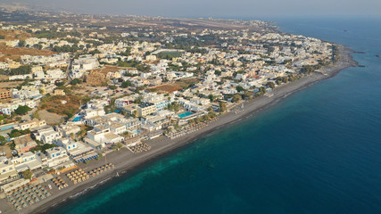 Fototapeta premium Aerial drone photo of famous seaside village and organised with sun-beds and umbrellas sandy beach of Kamari, Santorini island, Cyclades, Greece