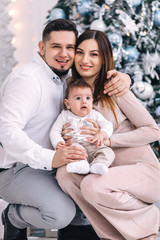 Fototapeta premium Dad, mom and little son on Christmas tree background. close up.