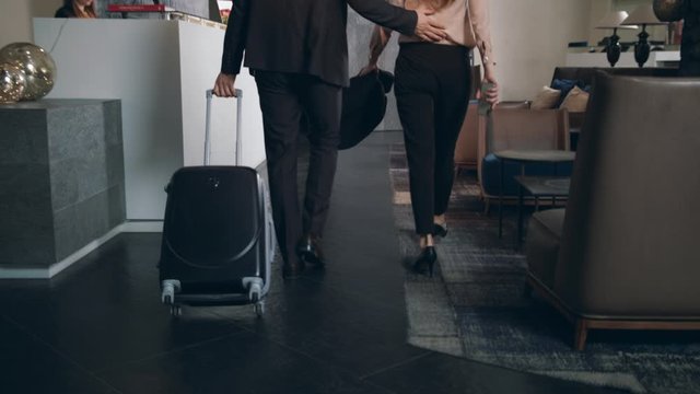 Business couple with suitcase arriving on hotel. Man check in hotel reception