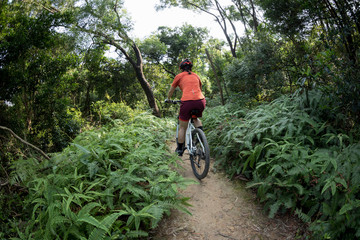 Fototapeta na wymiar Cross country biking woman cyclist riding mountain bike on tropical forest trail