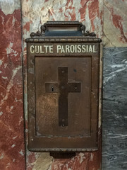 Old French church collection box with cross on marble wall
