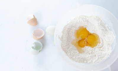 Three Raw Organic Eggs Broken into White Flour to make Dough 