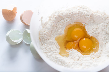 Three Raw Organic Eggs Broken into White Flour to make Dough 