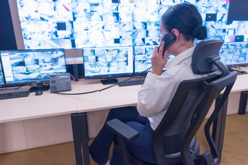 Security guard monitoring modern CCTV cameras in surveillance room. Female security guard in...