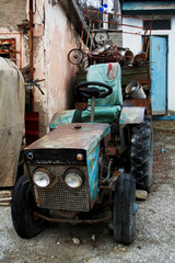 An old, abandoned tractor, blue with rust, stands along with garbage in the towns.