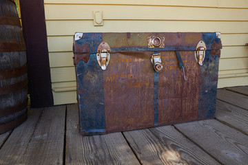 Old metal trunk sits forgotten on a wooden porch