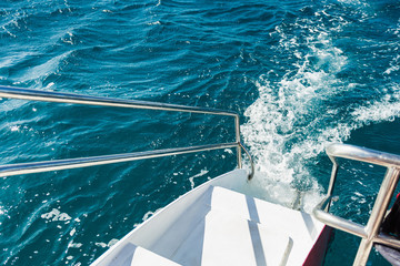 Railing stairs for diving on a catamaran.Ladder of a sailing yacht to the sea with the raging sea water. Stairs with iron railings and white steps for swimming