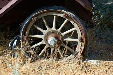 Fototapeta na wymiar Wooden spoke wheel on an early automobile sitting and rusting away near Virginia City, Nevada