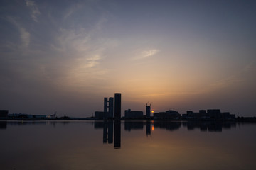 Obraz premium 海の水面に映る都市と夕日の風景