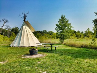Teepee setup at a campsite with a fire ring and picnic table
