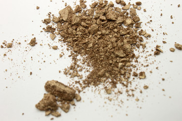 This is a photograph of a shimmery golden powder eyeshadow isolated on a White background