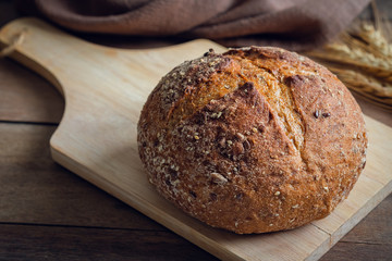 Bread loaf with whole grains on wooden board